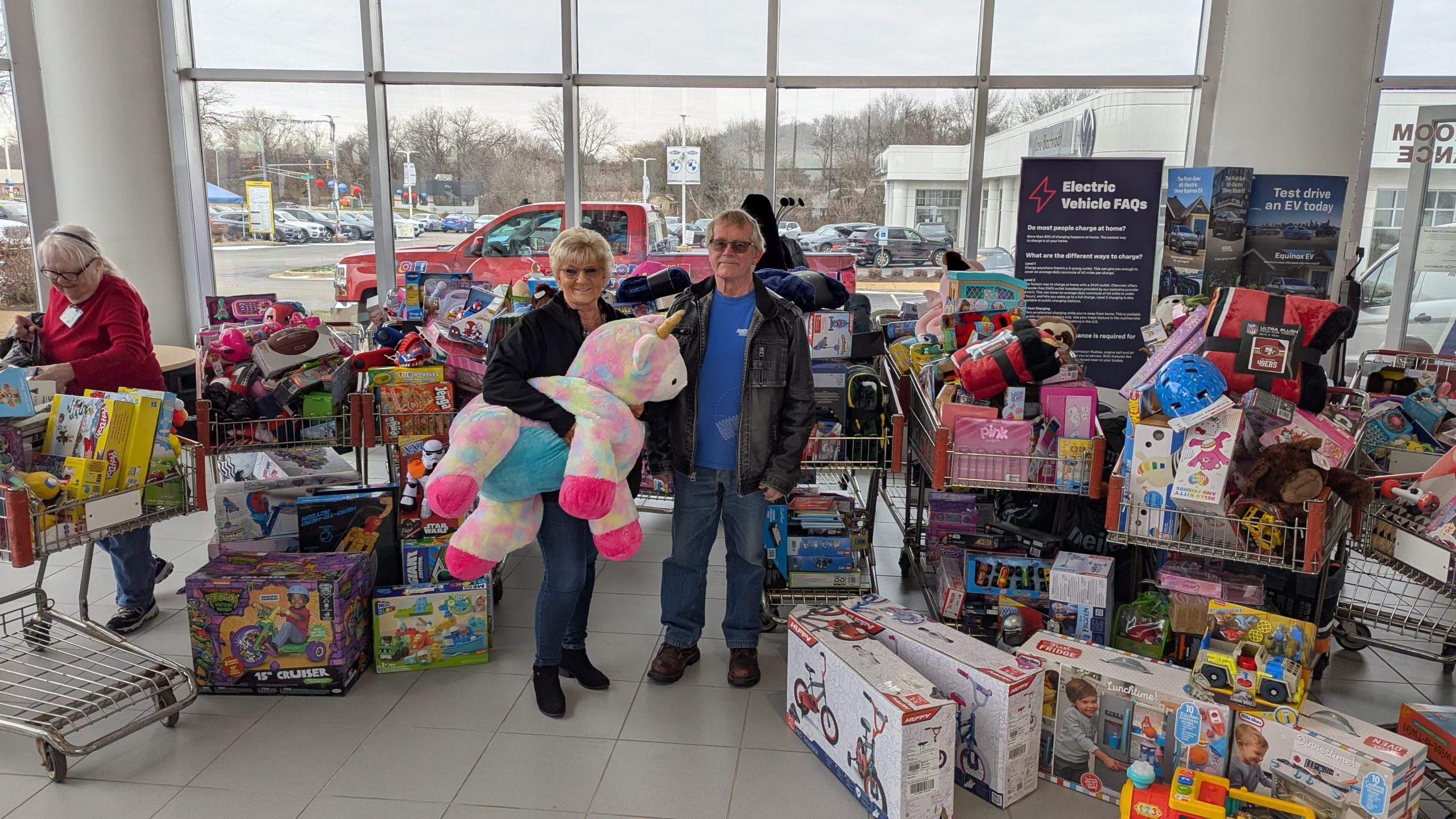 Two Bachrodt On State Employees with the toy donations behind them.